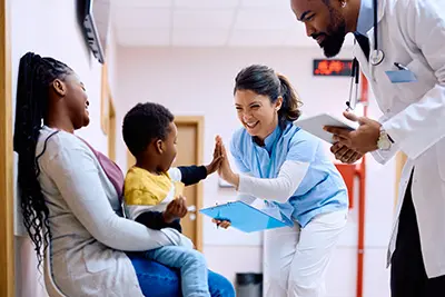 family at doctor's office, young child giving nurse a high-five